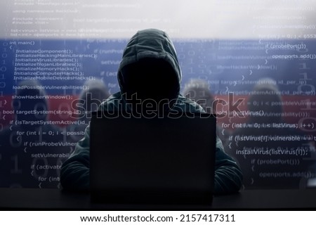 Russian hacker at laptop. Malware and virus danger from Russia. Man in hoodie and dark mask hacking. Dark net and cyber crime. Identity theft. Criminal at work. Troll army.  Royalty-Free Stock Photo #2157417311