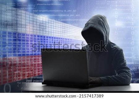 Russian hacker at laptop. Malware and virus danger from Russia. Man in hoodie and dark mask hacking. Dark net and cyber crime. Identity theft. Criminal at work. Troll army. Royalty-Free Stock Photo #2157417389