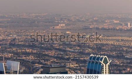 Houses and villas in Jumeirah Islands Community district with top of JLT skyscrapers timelapse. Aerial view from above with traffic on roads before sunset