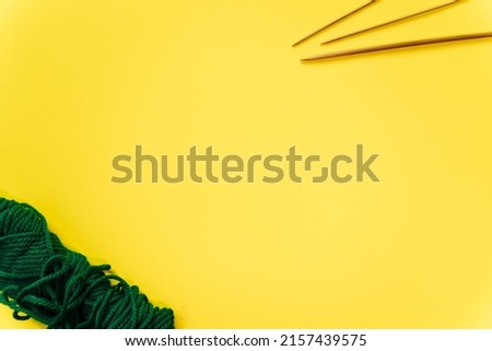  white wool knitting needles and a piece of knitting against a yellow background. High quality photo