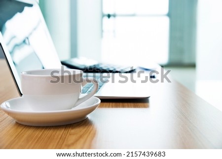 Laptop with coffee cup in office.