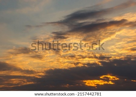Beautiful dramatic summer evening sky with beige and orange cumulus clouds and sun rays. Panoramic horizontal cloudscape. High-resolution photography. Design element. Copy space.