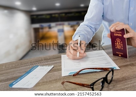 Man filling travel insurance application form with boarding pass and hispanic passport. inscription European Union Spain passport.