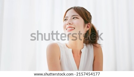 close up of asian woman with brunette ponytail smile look up in a white room Royalty-Free Stock Photo #2157454177