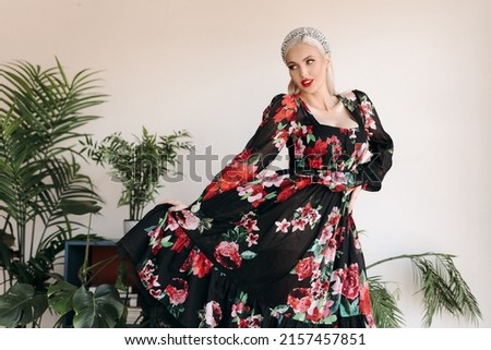 Luxurious blond girl of Slavic appearance poses in the studio with a green plant.
