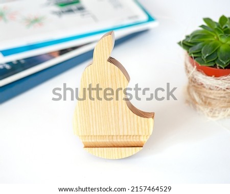 White wood pear shaped phone stand with magazines and succulents in the background
