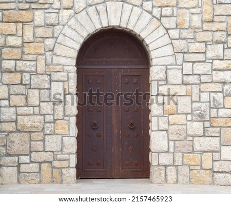 Old castle stone wall with closed big metal doors. Vintage gates. Retro doors, rock castle. Ancient concept