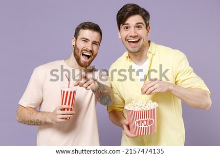 Young laughing joyful cool smiling happy men 20s friends together wearing casual t-shirt isolated on purple color background studio portrait People lifestyle friendship concept. Tattoo translate fun