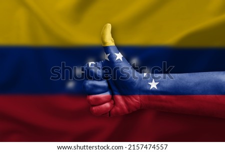 Hand making thumb up painted with flag of venezuela