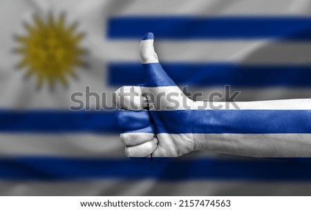 Hand making thumb up painted with flag of uruguay