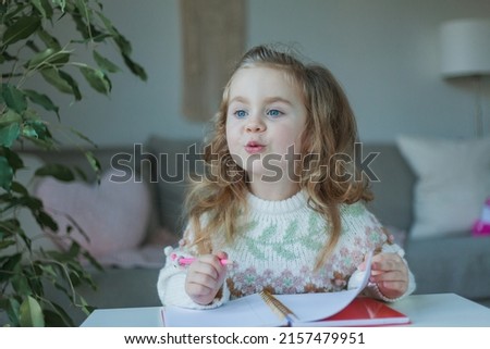 Little curly-haired cute blue-eyed girl 4 years old in a cozy house. Portrait of a happy child. Home school.