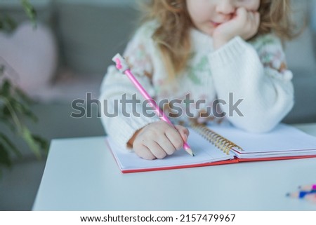Little curly-haired cute blue-eyed girl 4 years old in a cozy house. Portrait of a happy child. Home school.