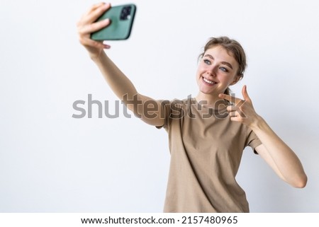 Image of excited brunette woman smiling and showing thumb up while taking selfie photo isolated over white background
