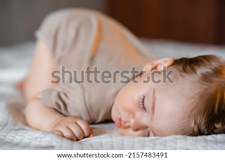 Portrait of a funny baby sleeping on his stomach on the bed at home. Close up. High quality photo Royalty-Free Stock Photo #2157483491