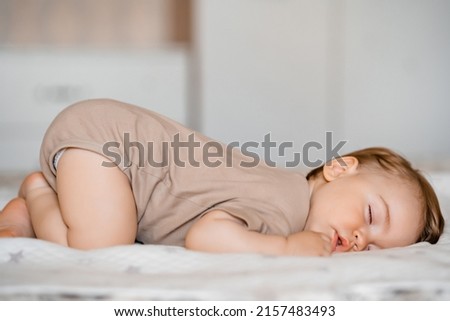 Funny baby with open mouth sleeping on his stomach on the bed at home. High quality photo Royalty-Free Stock Photo #2157483493