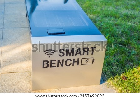 New smart bench in local public park used for charging mobile phones while providing wireless network Royalty-Free Stock Photo #2157492093
