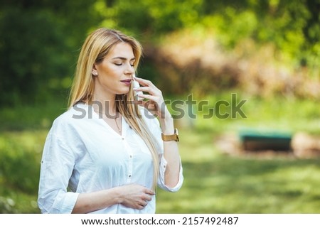 Taking nose drops because of pollen allergy. Woman is having flu and she is using nasal spray to help herself. Woman using nasal spray. Nasal spray to help a cold. Sick with a rhinitis woman  Royalty-Free Stock Photo #2157492487