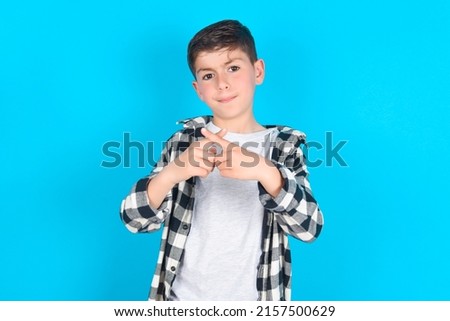 caucasian kid boy wearing plaid shirt over blue background has rejection angry expression crossing fingers doing negative sign.