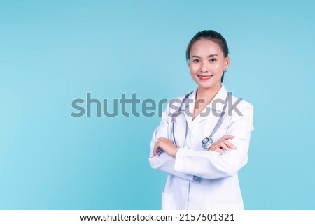 Happy smiling attractive Asian female woman doctor arms crossed confident, medical health care worker scientist clinical specialist expert in lab coat stethoscope, copyspace blue isolated background Royalty-Free Stock Photo #2157501321