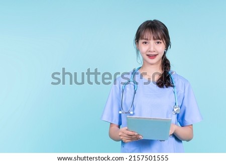 Happy smiling with Braces young Asian female doctor using smart digital tablet technology touch screen interacting, medical health care worker in surgical uniform, copyspace blue isolated background