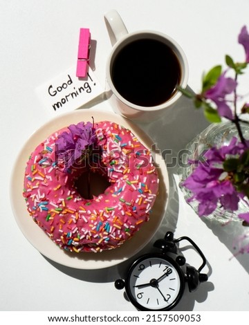 pink donut with pink flowers on a white background in graphic style. Selective focus. Donuts and pink flowers. Good morning.
