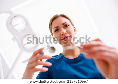 Low angle view of female dentist applying local anesthetic to patient before oral surgery procedure; doctor applying dermal fillers to patient Royalty-Free Stock Photo #2157510667