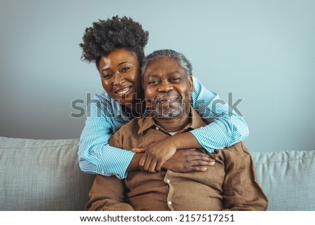 Smiling young woman sitting on sofa with happy older retired 70s father, enjoying pleasant conversation with cup of coffee tea together in living room, mature parents and grown children communication.