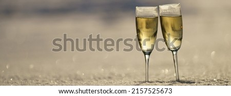 Photography of two glasses with golden champagne. Sunny winter day. White snow as background. Concept of holidays. Panoramic image