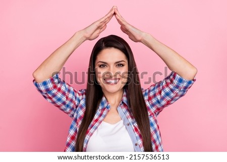 Photo of cheerful shiny woman wear plaid shirt showing arms roof smiling isolated pink color background