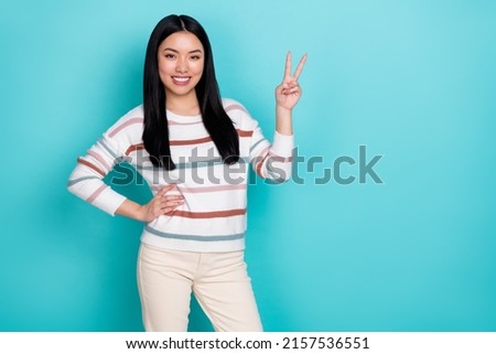 Photo of cool millennial lady show v-sign wear striped sweater isolated on turquoise color background