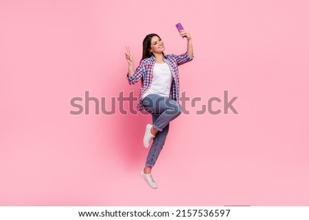 Full body photo of young brunette lady jump do selfie wear shirt jeans shoes isolated on pink background