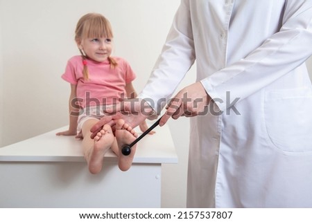 Doctor neuropathologist checks the plantar reflex on the leg of a little girl. Treatment and diagnosis of neurological diseases, tomahawk Royalty-Free Stock Photo #2157537807