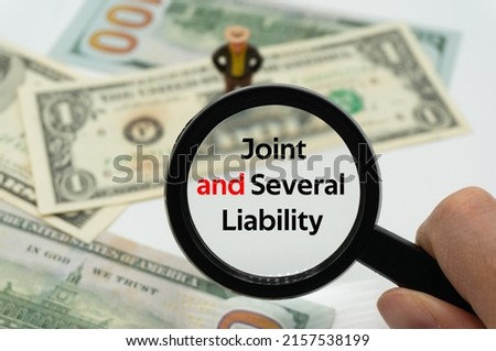 Joint and Several Liability.Magnifying glass showing the words.Background of banknotes and coins.basic concepts of finance.Business theme.Financial terms. Royalty-Free Stock Photo #2157538199