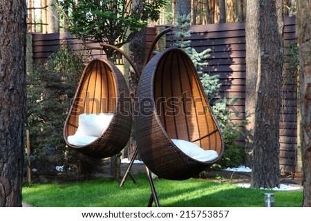 Round modern furniture plastic wicker chairs in garden  Royalty-Free Stock Photo #215753857