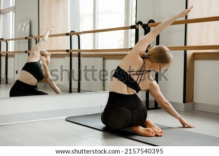 Beautiful girl stretches on a fitness mat in front of a mirror Royalty-Free Stock Photo #2157540395