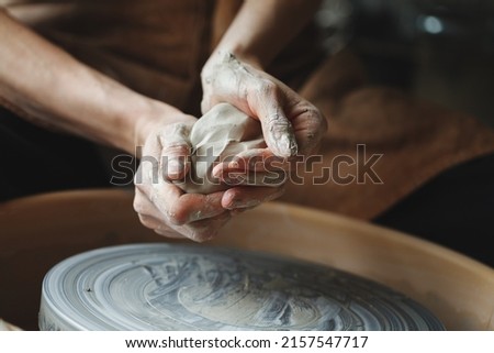 Woman hands working on pottery wheel making a clay pot, raw clay shaping, traditional craft Royalty-Free Stock Photo #2157547717