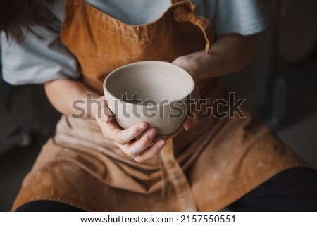 Pottery studio, artisan business, female potter hands holding ceramic bowl ready for firing in a kiln Royalty-Free Stock Photo #2157550551