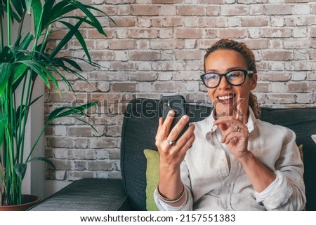 Happy pretty curly woman taking selfie, photo on mobile phone at home, using online app, virtual service for payment, making call. Satisfied cellphone user chatting, browsing on internet
