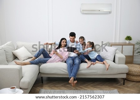 Happy family resting under air conditioner on white wall at home Royalty-Free Stock Photo #2157562307