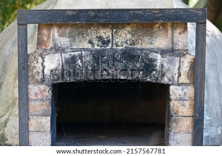 CLOSE VIEW OF AN OUTDOORS PIZZA OVEN UNDER A TREE