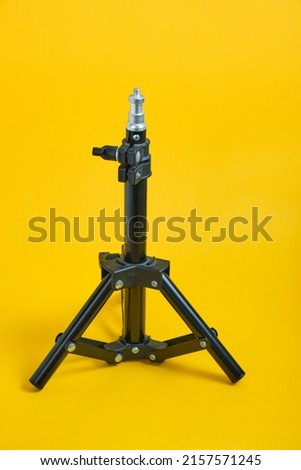 miniature tripod for photographic equipment on a yellow background