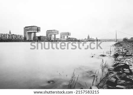 A grayscale shot of a calm lake against the clear sky captured from the coast