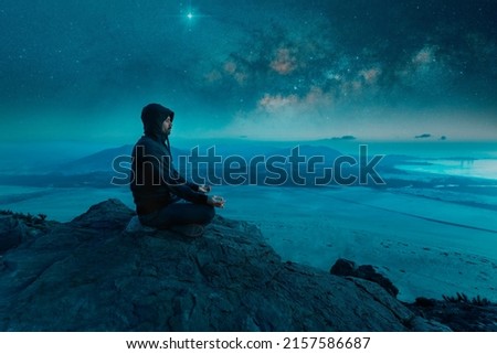 person sitting on the top of the mountain meditating at night with stars and  Milky Way background
