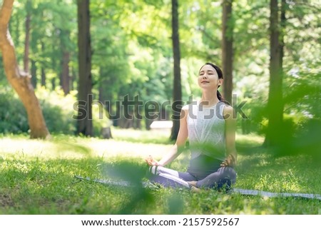 Asian woman meditating in the woods. Forest yoga. Mindfulness. Royalty-Free Stock Photo #2157592567