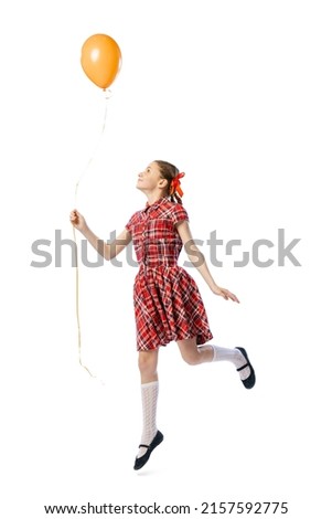 Portrait of beautiful little girl in retro skirt and shirt posing with air balloon isolated on white studio background. Concept of childhood, kids fashion, lifestyle, education, fun. Copy space for ad
