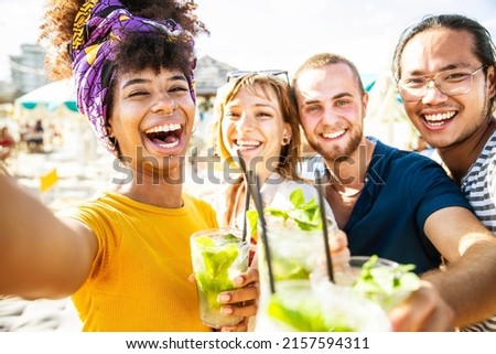 Multiracial friends cheering cocktails at beach party - Young people laughing together having fun on summer vacation - Friendship concept with guys and girls smiling outside on summertime holiday 