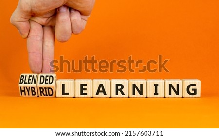Blended or hybrid learning symbol. Businessman turns cubes, changes words blended learning to hybrid learning. Orange background. Business, education, blended or hybrid learning concept. Copy space. Royalty-Free Stock Photo #2157603711