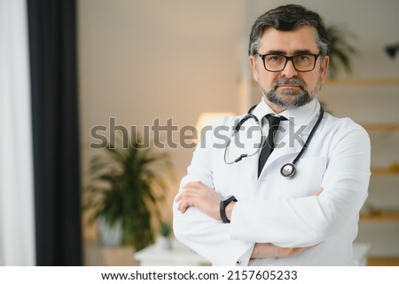 Portrait of healthcare worker. Image of senior male doctor wearing lab coat and standing at private clinic.
