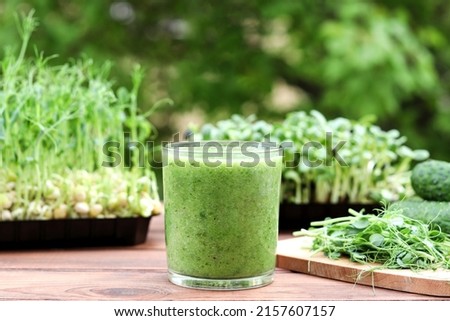 Green vegetable smoothie against background of greenery and microgreen. Healthy, vegan food, dieting concept. Selective focus Royalty-Free Stock Photo #2157607157