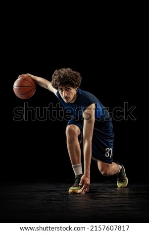 Dribbling. Professional basketball player in action and motion isolated on dark background. Concept of sport, competition, achievements, game. healthy lifestyle. Copy space for ad